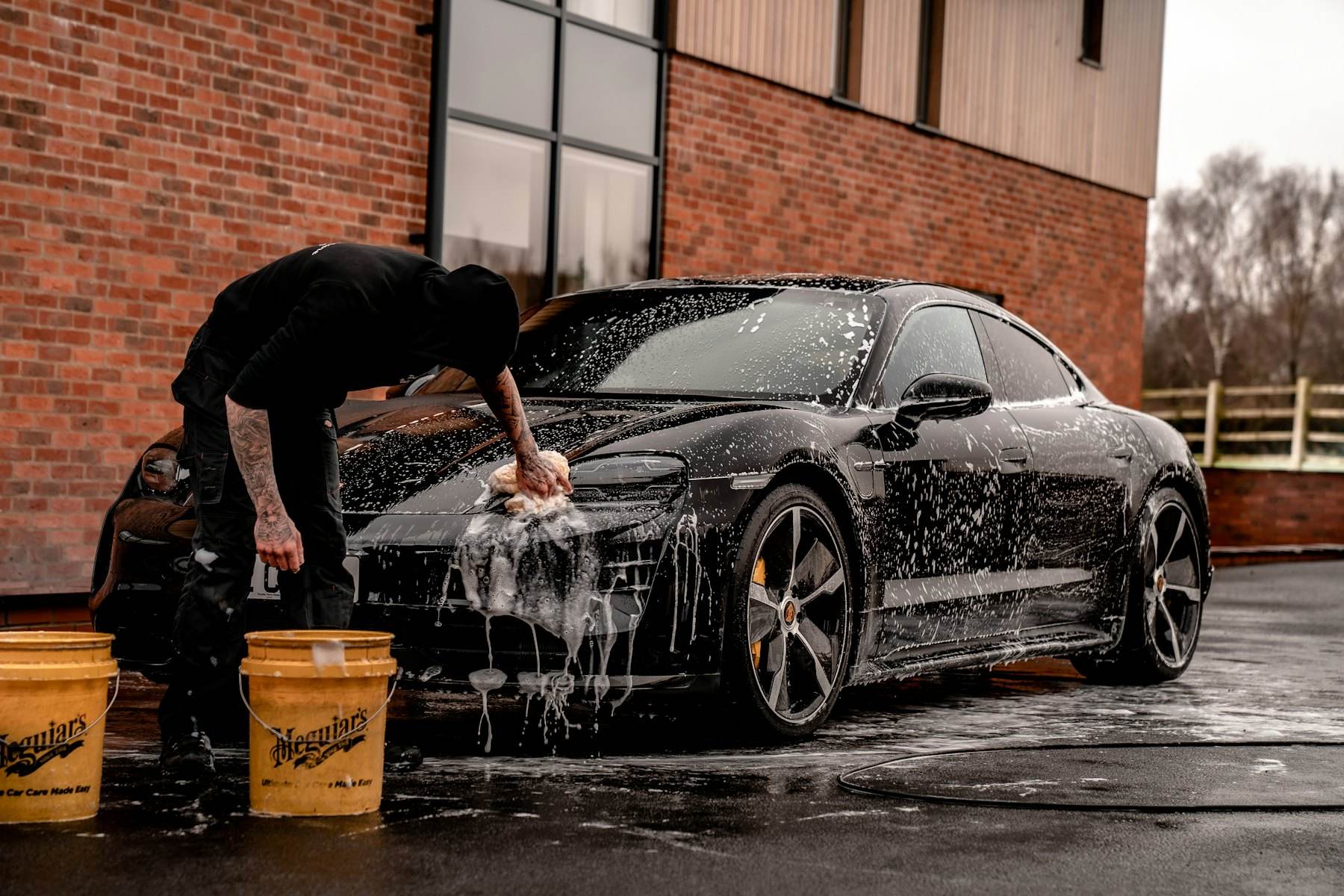 Black car being washed with snow foam